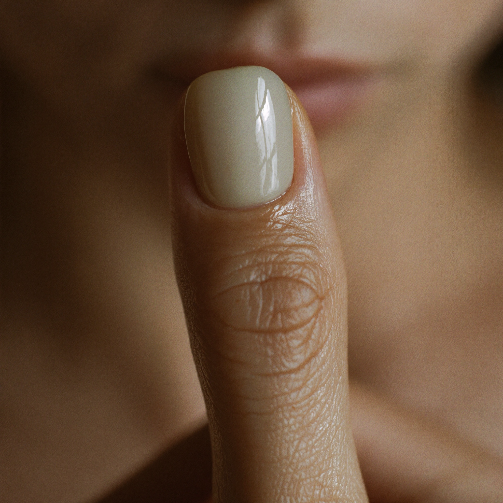 Makroaufnahme eines einzelnen manikürten Fingernagels mit dezent glänzendem, nudefarbenem Finish